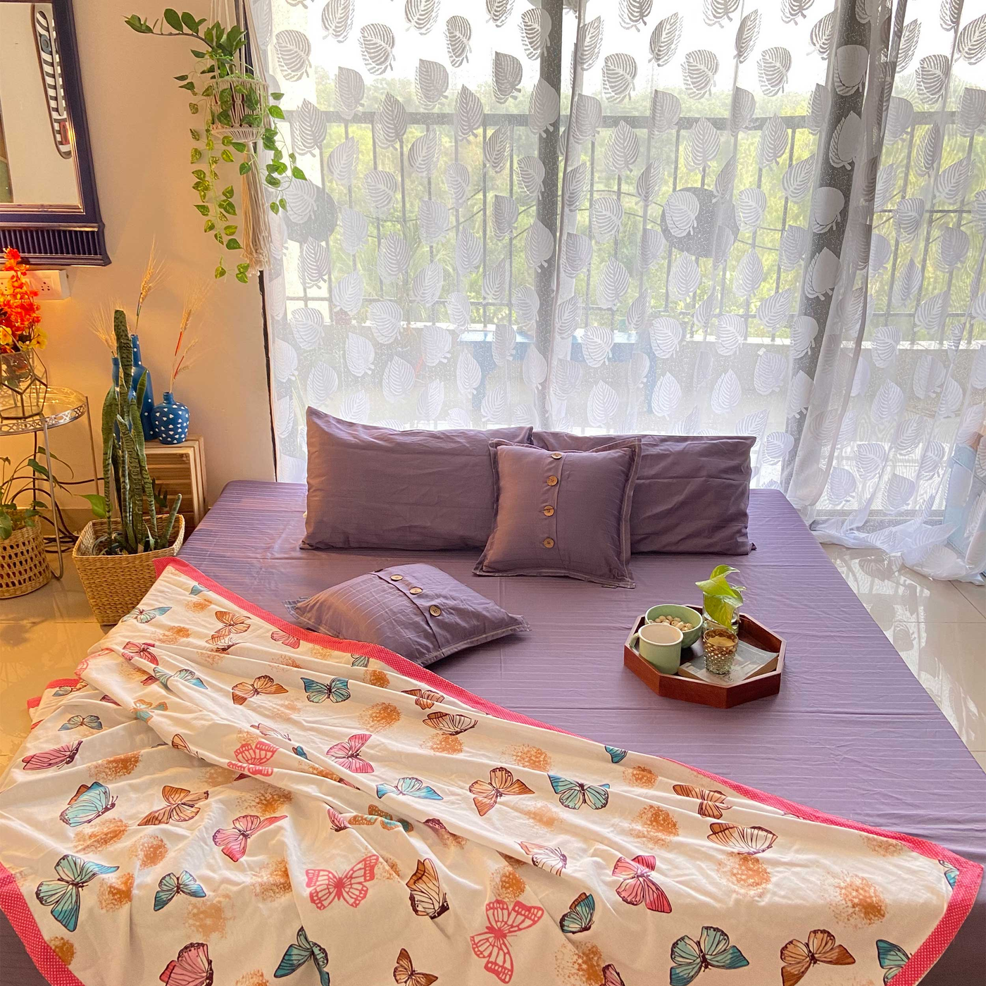 a purple sage fitted cotton bedsheet with cushion covers and a butterfly throw in the bed